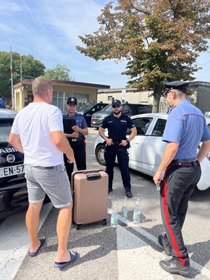 Polscy i włoscy policjanci z osobą cywilną w tle pojazdy i budynki.