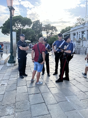 Na placu polski policjant i trzech włoskich policjantów rozmawiają z osoba cywilną.