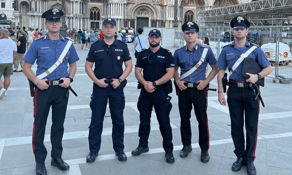 Dwóch polskich i trzech włoskich umundurowanych policjantów na tle zabytkowego budynku.