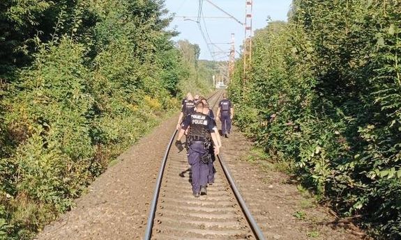 policjanci chodzą po torach, dookoła las