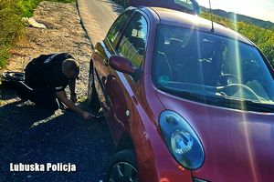 policjant wymienia koło w samochodzie