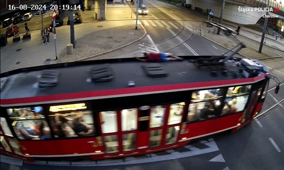 Zdjęcie przedstawia mężczyznę jadącego na dachu tramwaju