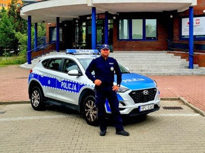 policjant stoi przed radiowozem