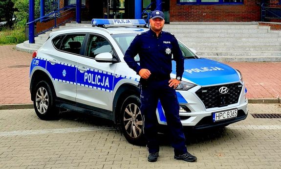 policjant stoi przed radiowozem