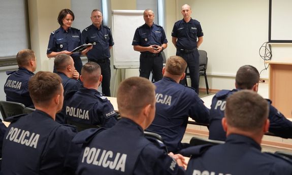 plecy policjantów, przed nimi stoją inni policjanci