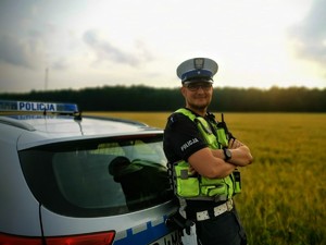 policjant stoi przed radiowozem