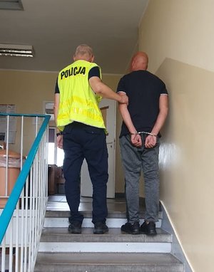 Policjant prowadzi zatrzymanego mężczyznę