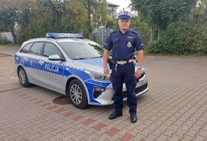 na zdjęciu umundurowany policjant, w tle radiowóz