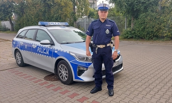 na zdjęciu umundurowany policjant, w tle radiowóz