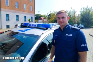 policjant stoi przy radiowozie