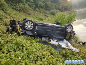 na zdjęciu przewrócone auto, w tle jezioro