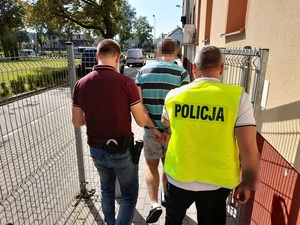 dwóch policjantów prowadzi zatrzymanego mężczyznę