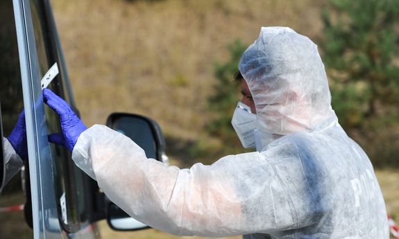 policjant w specjalnym stroju bada samochód