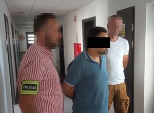 dwóch policjantów prowadzi zatrzymanego mężczyznę