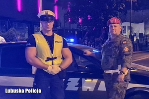 Wspólne zdjęcie policjanta wraz z żandarmem na tle radiowozu Żandarmerii Wojskowej