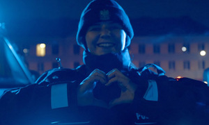 Policjantka w zimowym umundurowaniu układa ręce w kształt serca.