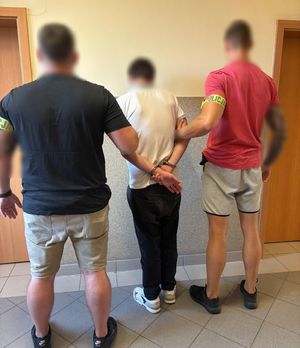 dwaj policjanci z zatrzymanym w kajdankach