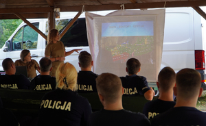 kobieta przemawia do policjantów siedzących na krzesłach w trakcie szkolenia