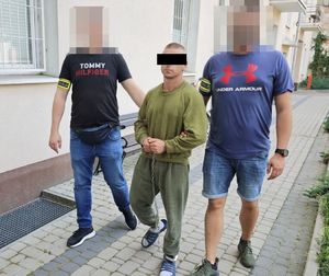 dwóch policjantów prowadzi zatrzymanego mężczyznę