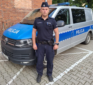 policjant stoi przed radiowozem