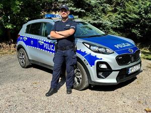 policjant stoi obok radiowozu