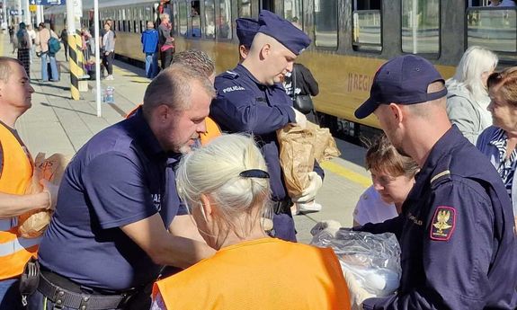 policjanci dają żywność ludziom