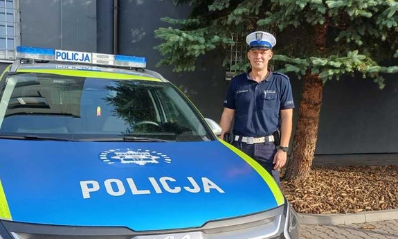 policjant stoi przy radiowozie policyjnym