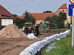 policjant pomagający napełniać worki z piaskiem