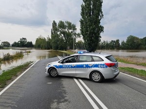 radiowóz stoi w poprzek drogi, w głębi droga zalana przez wodę