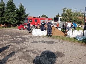 policjanci wspólnie z mieszkańcami napełniają worki z piaskiem