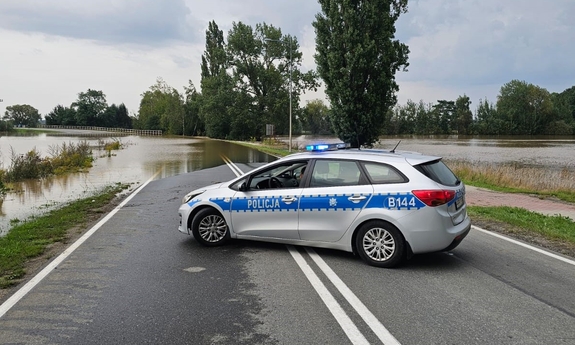 radiowóz stoi w poprzek drogi, w głębi droga zalana przez wodę