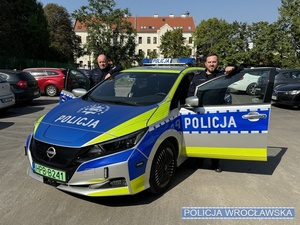 policjanci stoją przy radiowozie