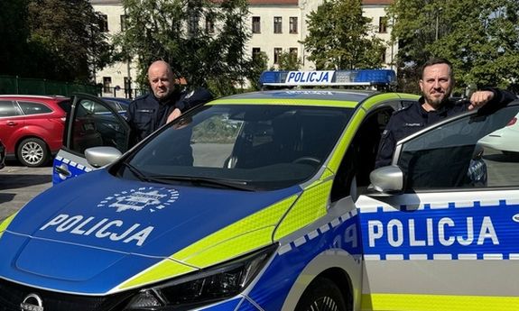 policjanci stoją przy radiowozie