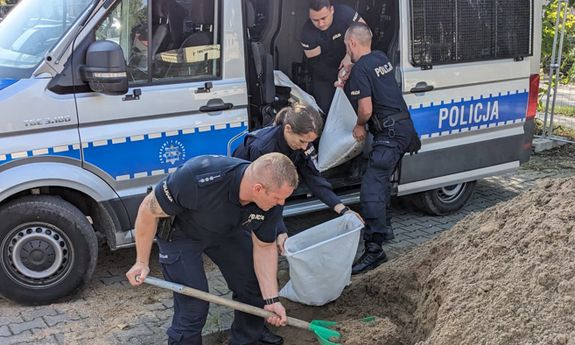 policjanci napełniają worki piaskiem