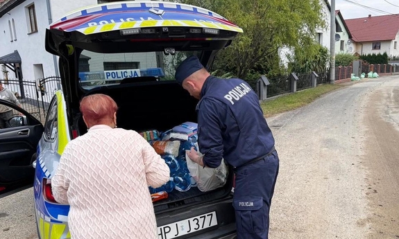 Policjant przekazuje paczkę potrzebującej kobiecie