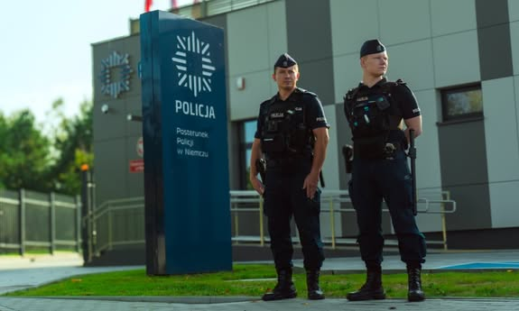 dwóch policjantów stoi przed nowym budynkiem policji