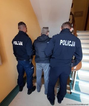 policjanci stoją z mężczyzną na klatce schodowej