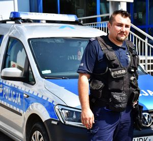 policjant stoi przy radiowozie