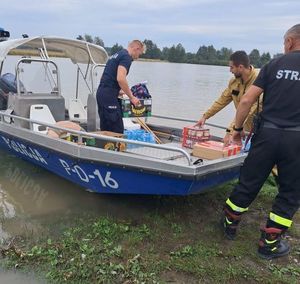 policjanci ładują rzeczy na łódź