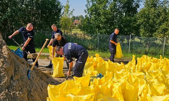 policjanci wsypują piasek do worków