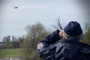 policjant spogląda na lecący śmigłowiec