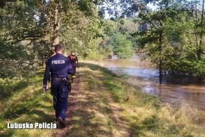 policjant idą wałem wzdłuż rzeki