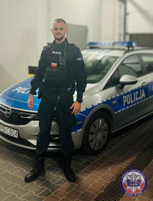 policjant stoi przy radiowozie policyjnym