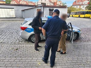 policjant pracowniczka cywilna oraz osoba w kryzysie bezdomności przy radiowozie