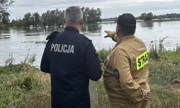 strażak pokazuje policjantowi poziom wody