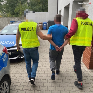 dwaj policjanci z zatrzymanym przy radiowozie