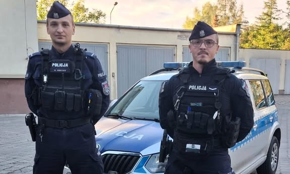 dwóch policjantów stoi przed radiowozem