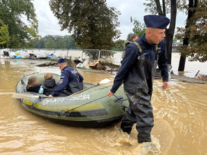 policjanci transportują ludzi na łódkach.