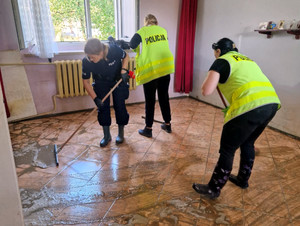 policjanci pomagają przy sprzątaniu mieszkania, mopują podłogę.