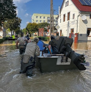 policjanci transportują ludzi na łódkach.